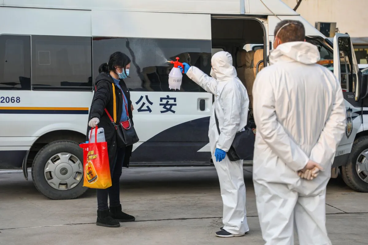 This photo taken on Feb. 3, 2020 shows a medical staff member (C) spraying disinfectant on a patient after returning from a hospital and re-entering a quarantine zone in Wuhan, the epicentre of the new coronavirus outbreak, in China's central Hubei province. (STR/AFP via Getty Images)