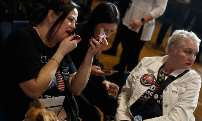 A woman with her dog applies lipstick as she attends Democratic presidential candidate former Vice President Joe Biden's Iowa caucus night event at Drake University in Des Moines, Iowa, on Feb. 3, 2020. (Joshua Lott/Getty Images)