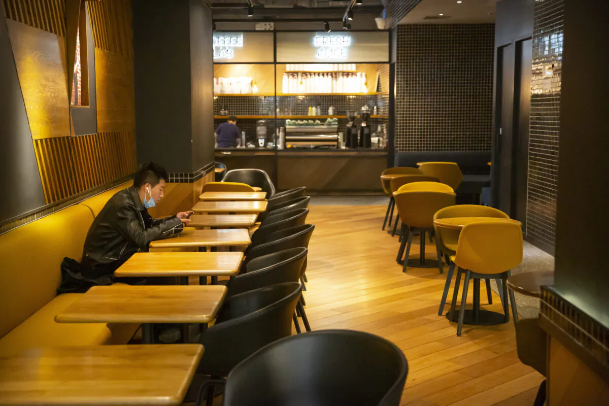 A man wearing a face mask waits for his food at an empty restaurant in Beijing, China on Jan. 28, 2020. (Mark Schiefelbein/AP)
