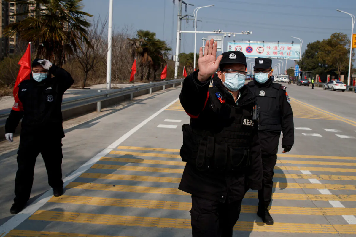 Security personnel attempt to prevent the photographer from taking pictures at a checkpoint at the Jiujiang Yangtze River Bridge as the country is hit by an outbreak of the novel coronavirus, in Jiujiang, Jiangxi Province, China, on Feb. 4, 2020. (Thomas Peter/Reuters)
