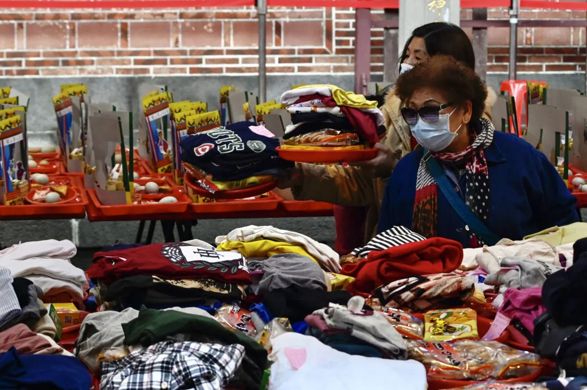 People wearing protective masks pray beside their clothes laid out on a table, at a Taoist Baoan temple in Taipei on Feb. 4, 2020. Taiwan has uncovered 10 cases of the new coronavirus so far, including two female Chinese nationals in their 70s who arrived in the country as part of a tour group. (Sam Yeh/AFP via Getty Images)