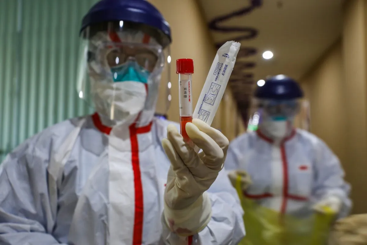 A medical staff member showing a test tube after taking samples from a person to be tested for the new coronavirus at a quarantine zone in Wuhan City, Hubei Province, China on Feb. 4, 2020. (STR/AFP via Getty Images)