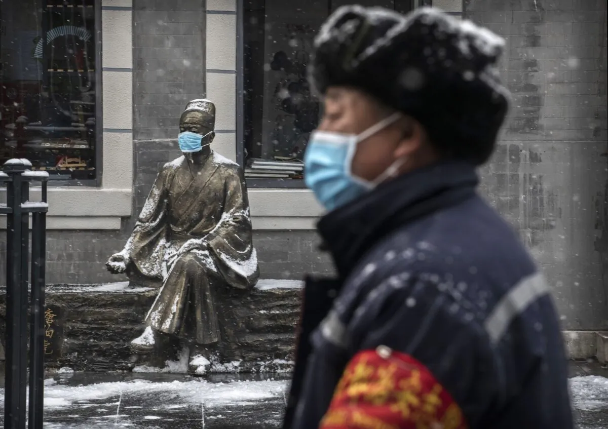A Chinese man wears a protective mask as he walks during a snowfall in an empty commercial street in Beijing, China on Feb. 5, 2020. (Kevin Frayer/Getty Images)