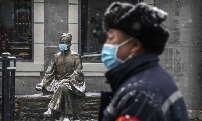A Chinese man wears a protective mask as he walks during a snowfall in an empty commercial street in Beijing, China on Feb. 5, 2020. (Kevin Frayer/Getty Images)