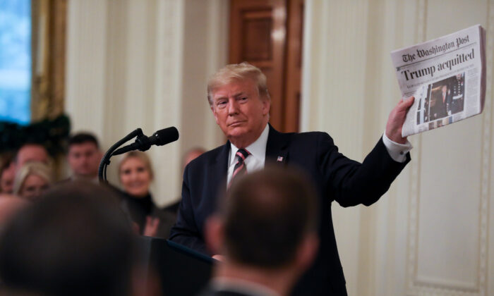 President Donald Trump holds up a newspaper during his victory speech a day after being acquitted on two articles of impeachment, in the East Room of the White House on Feb. 6, 2020. (Charlotte Cuthbertson/The Epoch Times)