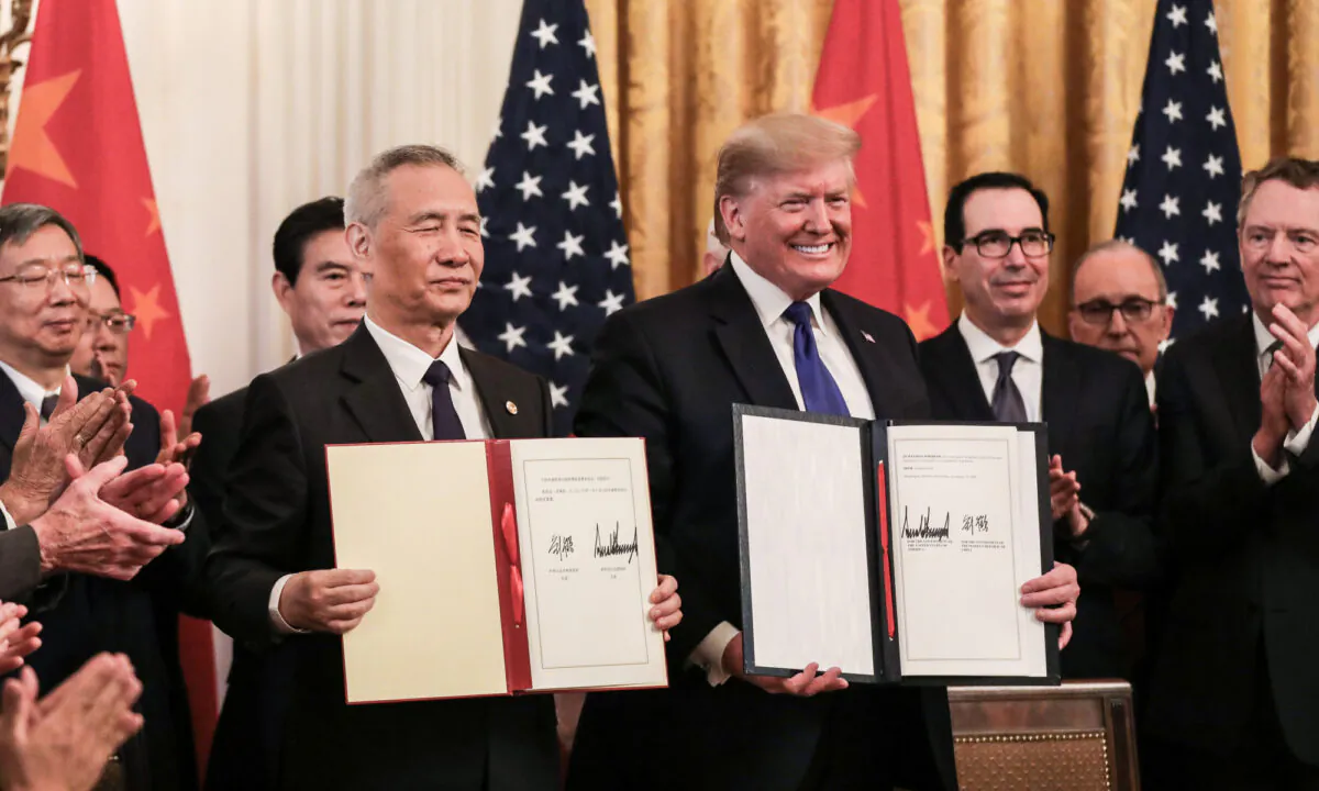 Chinese Vice Premier Liu He (L) and President Donald Trump during the signing of the phase one trade deal, surrounded by officials, in the East Room of the White House on Jan. 15, 2020. (Charlotte Cuthbertson/The Epoch Times)
