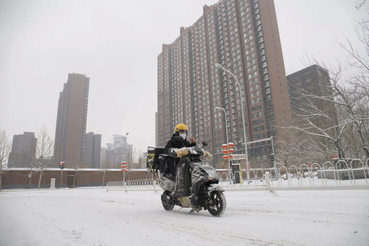 A food delivery worker rides his bike amid snow at a residential compound, as the country is hit by an outbreak of the novel coronavirus, in Beijing, China on Feb. 6, 2020.  (Reuters)