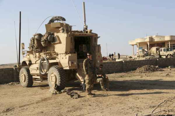 U.S. Army soldiers stand outside their armored vehicle