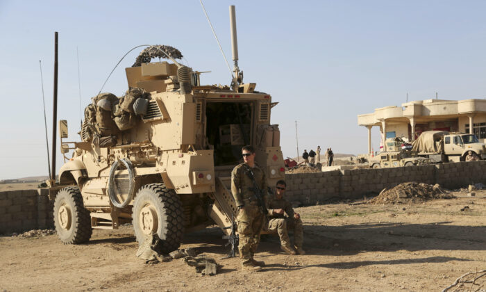 U.S. Army soldiers stand outside their armored vehicle on a joint base with the Iraqi army, south of Mosul, Iraq. ( Khalid Mohammed/AP)