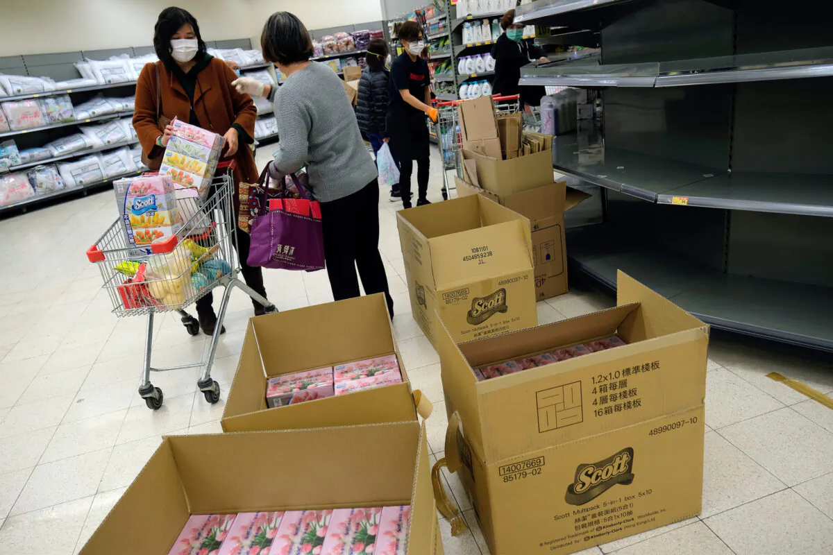Customers wear masks as they pick facial tissues in a supermarket, following the outbreak of a new coronavirus, in Hong Kong, China on Feb. 7, 2020. (Tyrone Siu/Reuters)