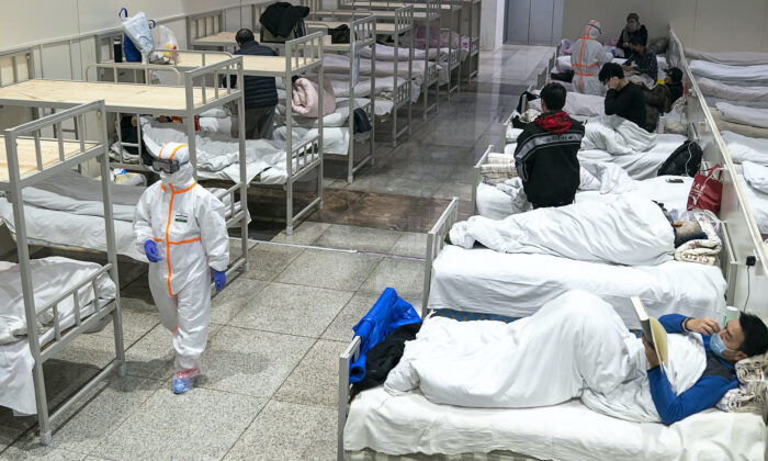 Medical worker in protective suit walks by patients diagnosed with the coronaviruses in a temporary hospital transformed from an exhibition center in Wuhan in central China's Hubei province on Feb. 5, 2020. (Chinatopix via AP)