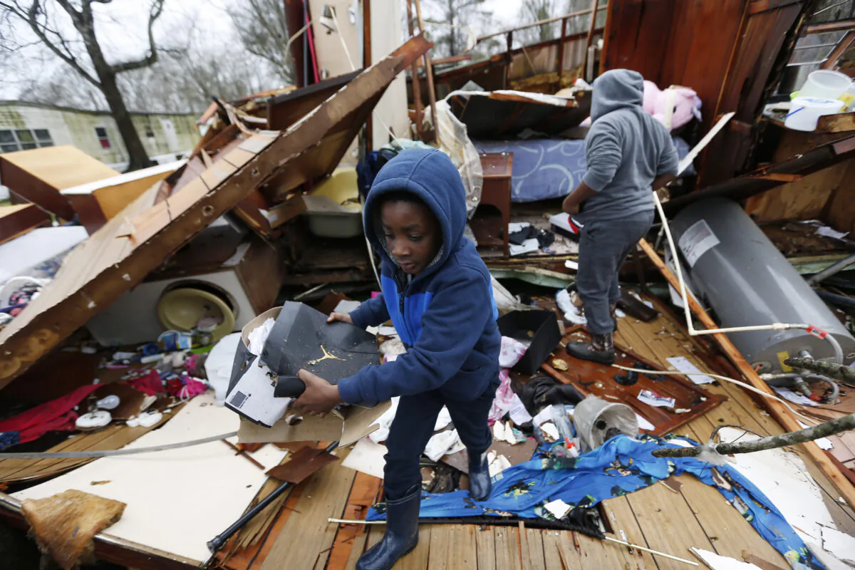 Emma Carter's grandsons comb the remains of her mobile home, looking for salvageable clothing and personal items after severe weather hit the area, in Pickens, Miss., on Feb. 6, 2020. (Rogelio V. Solis/AP)