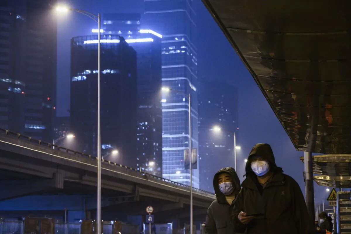 Chinese men wear protective masks as they wait for the bus on a nearly empty street in the normally busy Central Business District during the Friday rush hour in Beijing, China on Feb. 7, 2020. (Kevin Frayer/Getty Images)
