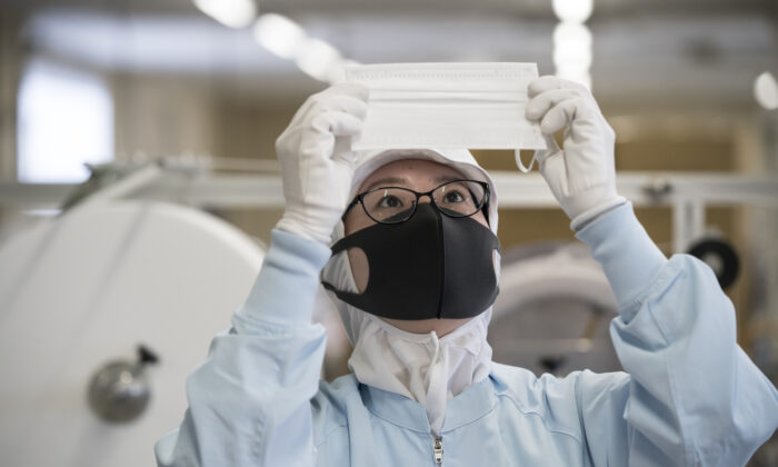 An employee inspects a disposable face mask on the production line of the Yokoi Co. Ltd. factory in Nagoya, Japan on Feb. 06, 2020. (Tomohiro Ohsumi/Getty Images)