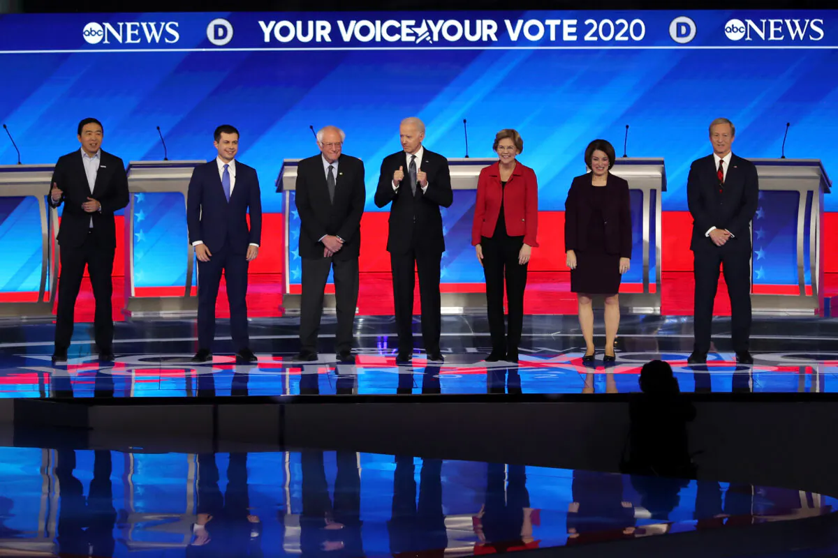Then-Democratic presidential candidates Andrew Yang, former South Bend, Indiana Mayor Pete Buttigieg, Sen. Bernie Sanders (I-Vt.), Joe Biden, Sen. Elizabeth Warren (D-Mass.), Sen. Amy Klobuchar (D-Minn.), and Tom Steyer stand on stage at the start of the Democratic presidential primary debate in the Sullivan Arena at St. Anselm College in Manchester, New Hampshire on Feb. 7, 2020. (Joe Raedle/Getty Images)