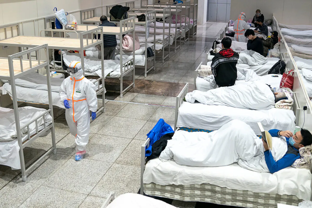 Medical workers in protective suits attend to patients at the Wuhan International Conference and Exhibition Center, which has been converted into a makeshift hospital to receive patients with mild symptoms caused by the novel coronavirus, in Wuhan, Hubei Province, China on Feb. 5, 2020. (China Daily via Reuters)