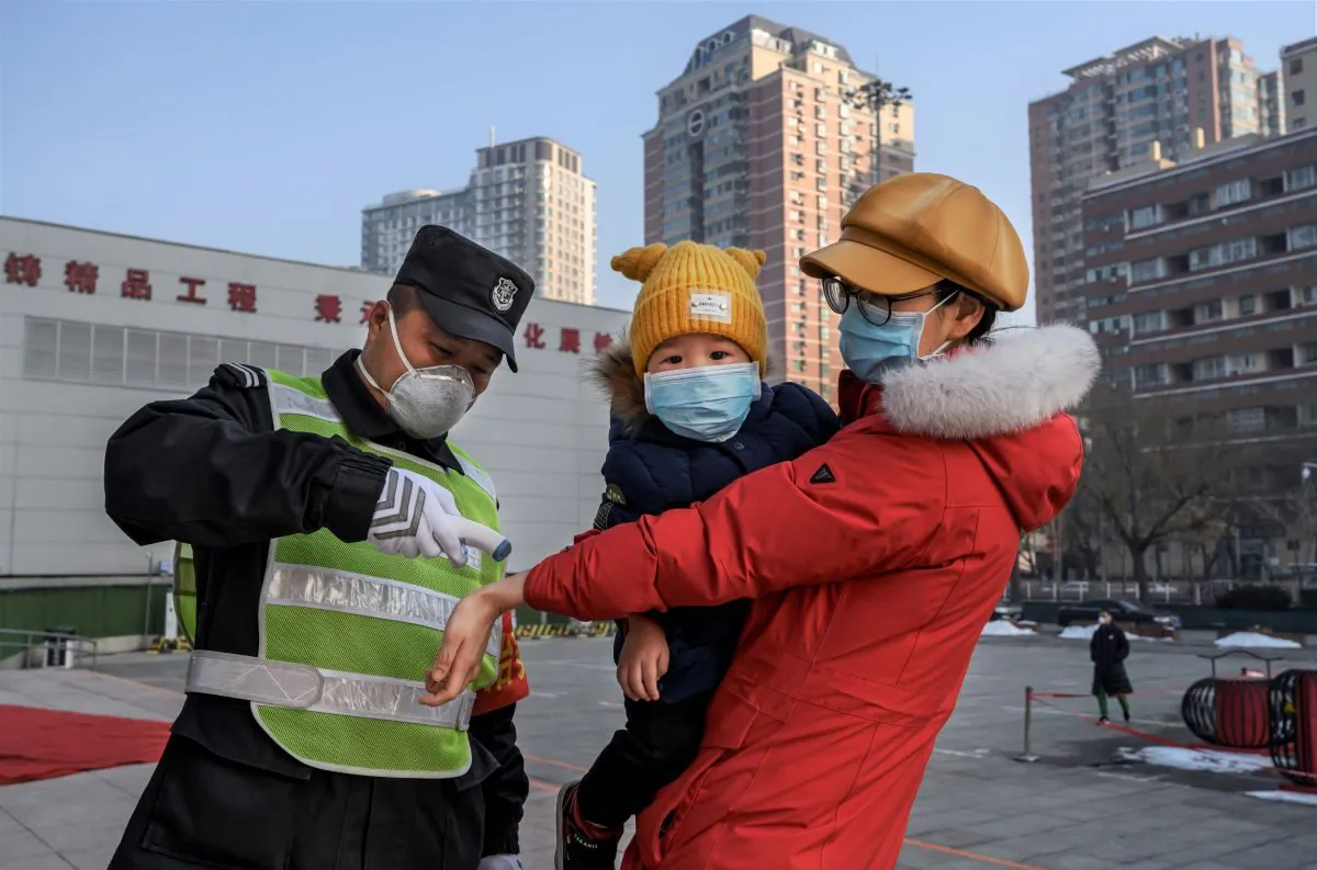 A Chinese woman wears a protective mask as she has her temperature checked before entering a park with her child in Beijing, China, on Feb. 9, 2020. (Kevin Frayer/Getty Images)