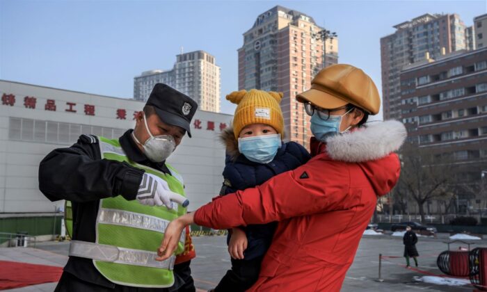 A Chinese woman wears a protective mask as she has her temperature checked before entering a park with her child in Beijing, China, on Feb. 9, 2020. (Kevin Frayer/Getty Images)