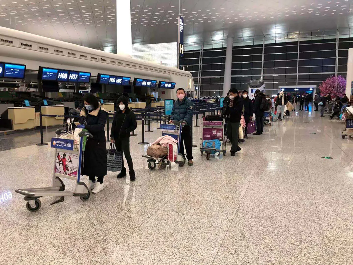 Passengers queue to board a cargo plane, chartered by the U.S. State Department to evacuate Americans and Canadians from China due to the outbreak of novel Coronavirus, at Wuhan Tianhe International Airport in Wuhan, China , on Feb. 7, 2020. (Courtesy of Edward Wang via Reuters)