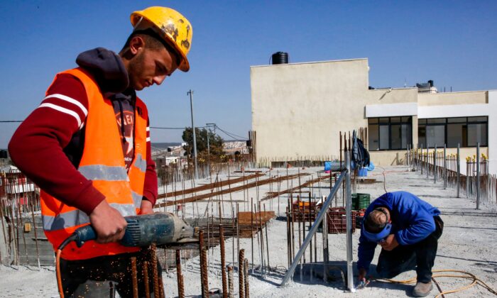 A construction worker saws steel rods at the site of a school that was funded by the U.S Agency for International Development (USAID) in Al-Jabaa, in the West Bank, on Jan. 22, 2019.  (HAZEM BADER/AFP via Getty Images)