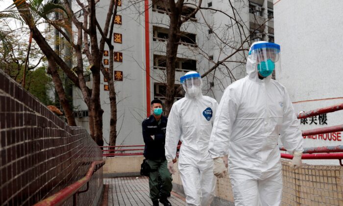 Health workers in protective gears walk as they evacuate residents from a public housing building, following the outbreak of the novel coronavirus, outside Hong Mei House, at Cheung Hong Estate in Hong Kong, China on Feb. 11, 2020. (Tyrone Siu/Reuters)