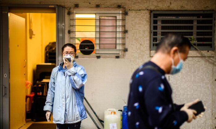 A woman wearing a face mask uses her phone next to containers of hydrogen peroxide in Hong Kong on Feb. 11, 2020. (Anthony Wallace/AFP via Getty Images)