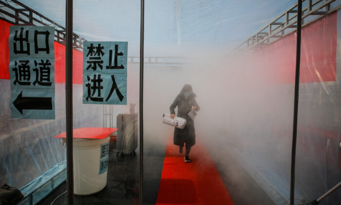 A woman wearing a face mask walks through a device that sprays disinfectant at an entrance to a residential compound, following an outbreak of the novel coronavirus in the country, in Tianjin, China on Feb. 11, 2020. (cnsphoto via Reuters)