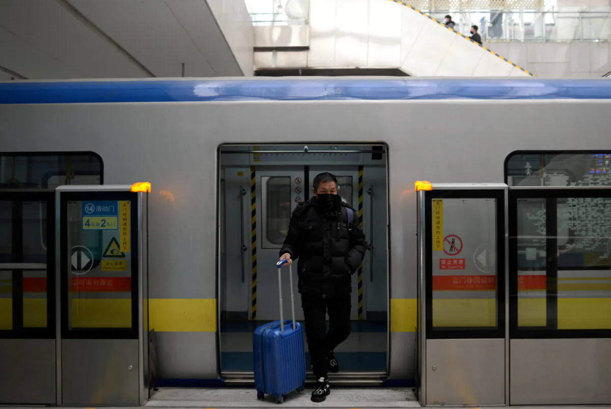 A man wearing a face mask walks out of the subway with a suitcase in the morning after the extended Lunar New Year holiday caused by the novel coronavirus outbreak, at the Xierqi subway station, in Beijing, China on Feb. 10, 2020. (ingshu Wang/Reuters)