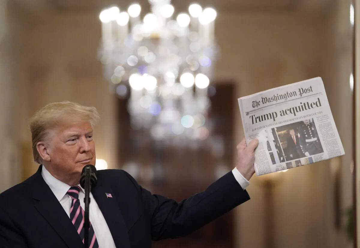 President Donald Trump holds a copy of The Washington Post as he speaks in the East Room of the White House one day after the U.S. Senate acquitted on two articles of impeachment, on Feb. 6, 2020. (Drew Angerer/Getty Images)