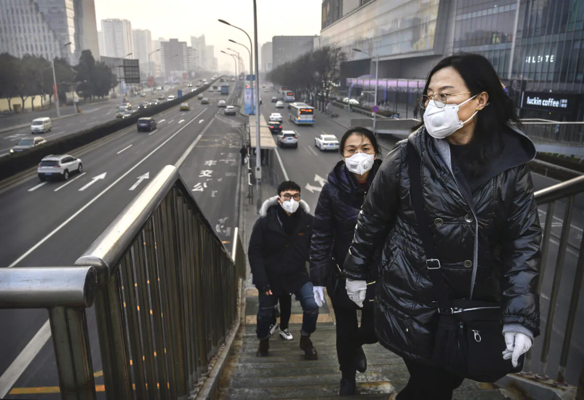 People wear protective masks as they cross a footbridge at a mall in Beijing on Feb. 11, 2020. (Kevin Frayer/Getty Images)