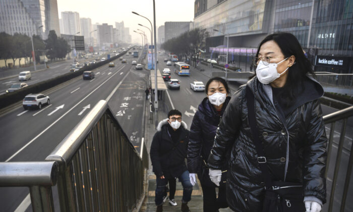 People wear protective masks as they cross a footbridge at a mall in Beijing on Feb. 11, 2020. (Kevin Frayer/Getty Images)