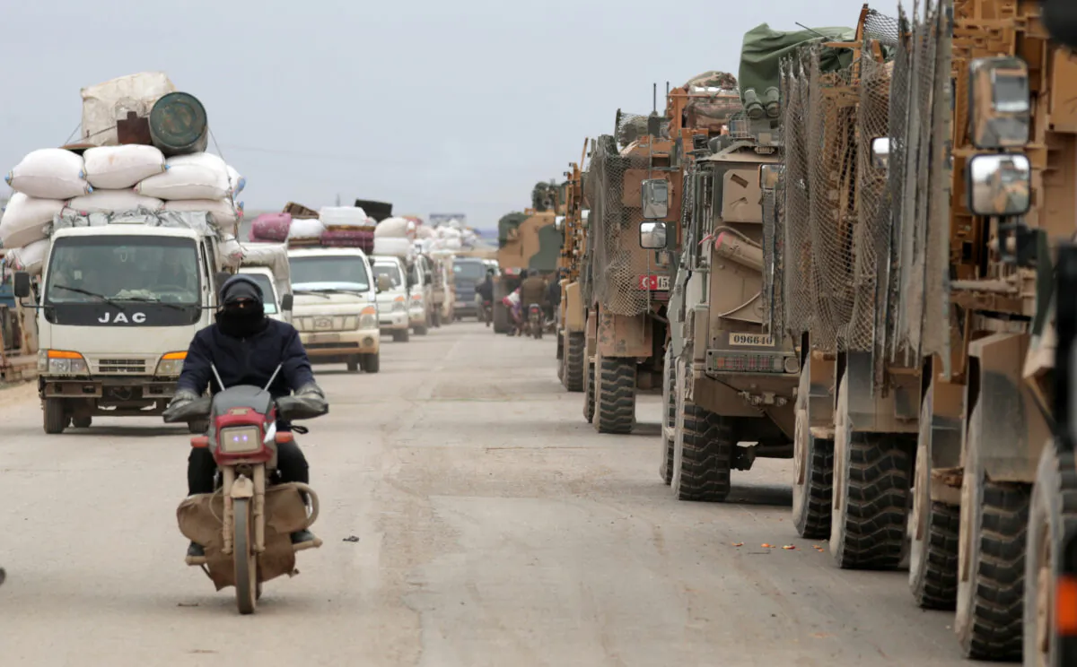 A man rides on a motorbike past Turkish military vehicles in Hazano near Idlib, Syria, on Feb. 11, 2020. (Khalil Ashawi/Reuters)