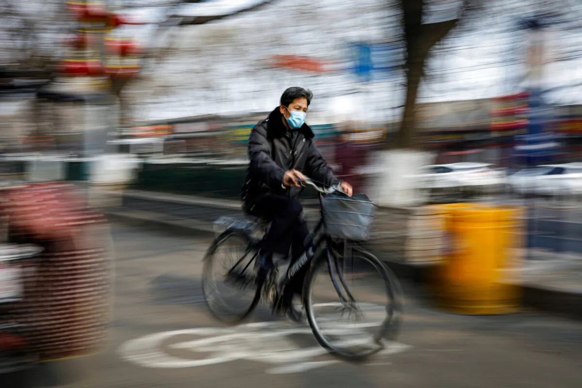 A man wearing a face mask rides a bicycle, as the country is hit by an outbreak of the novel coronavirus, in Beijing, China on Feb. 12, 2020. (Carlos Garcia Rawlins/Reuters)