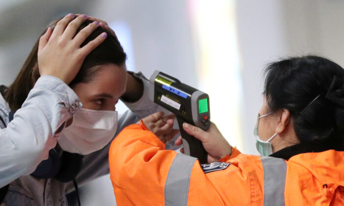 A worker checks the temperature of a passenger arriving into Hong Kong International Airport with an infrared thermometer, following the coronavirus outbreak in Hong Kong, China, on Feb. 7, 2020. (Hannah McKay/Reuters)