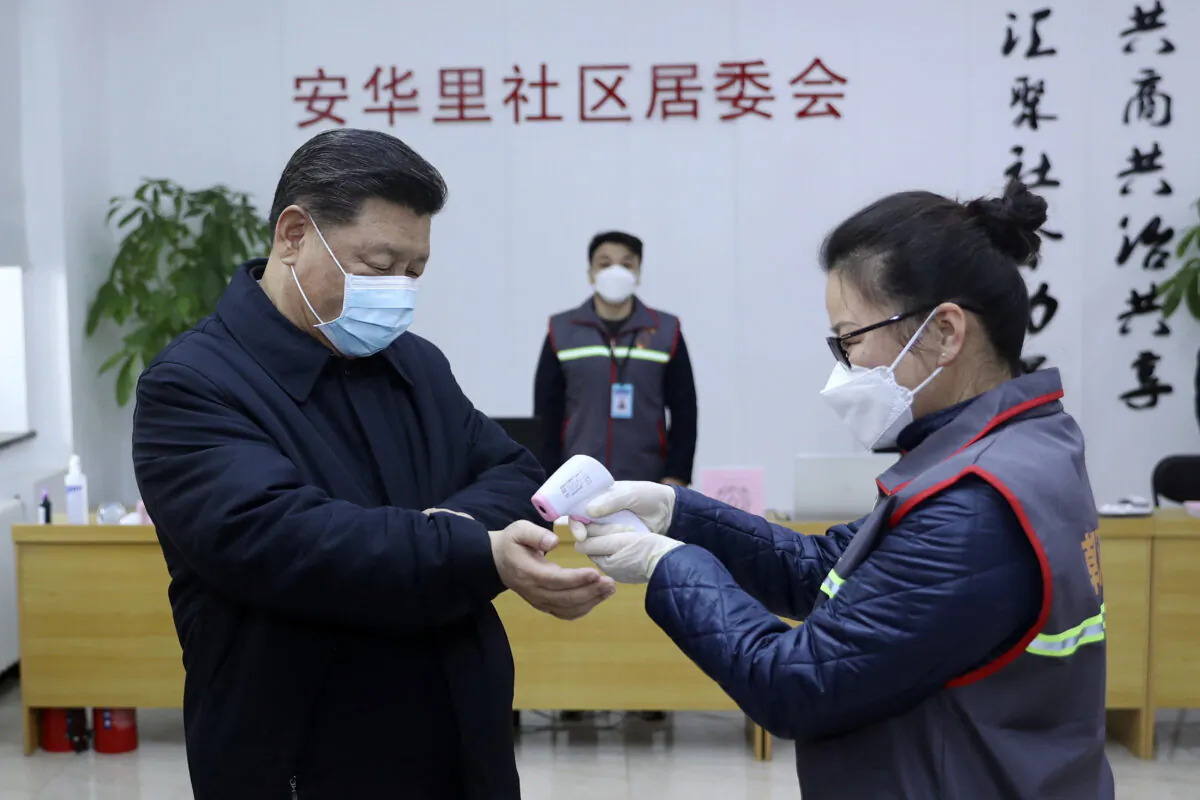 Chinese leader Xi Jinping, left, wearing a protective face mask, receives a temperature check while visiting a community health center in Beijing, China on Feb. 10, 2020. (Pang Xinglei/Xinhua via AP)