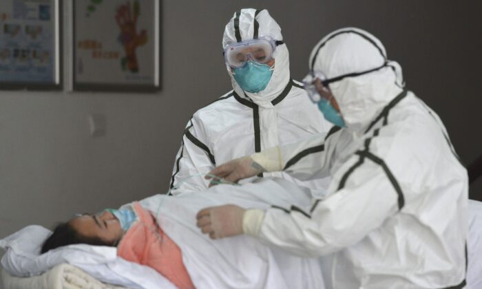 Medical workers in protective suits move a coronavirus patient into an isolation ward at the Second People's Hospital in Fuyang in central China's Anhui Province on Feb. 1, 2020. (Chinatopix via AP)