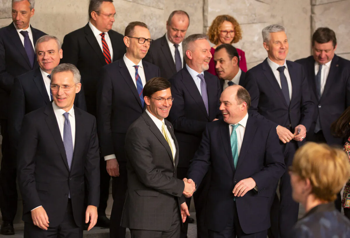 U.S. Secretary for Defense Mark Esper, front center, shakes hands with British Defense Minister Ben Wallace during a group photo of NATO defense ministers at NATO headquarters in Brussels on Feb. 12, 2020. (Virginia Mayo/ AP Photo)