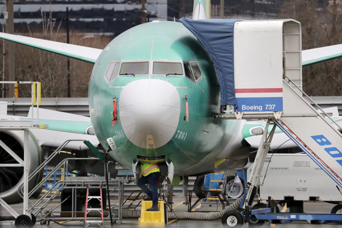 A worker looks up underneath a Boeing 737 MAX jet in Renton, Washington, on Dec. 16, 2019. (Elaine Thompson/AP)