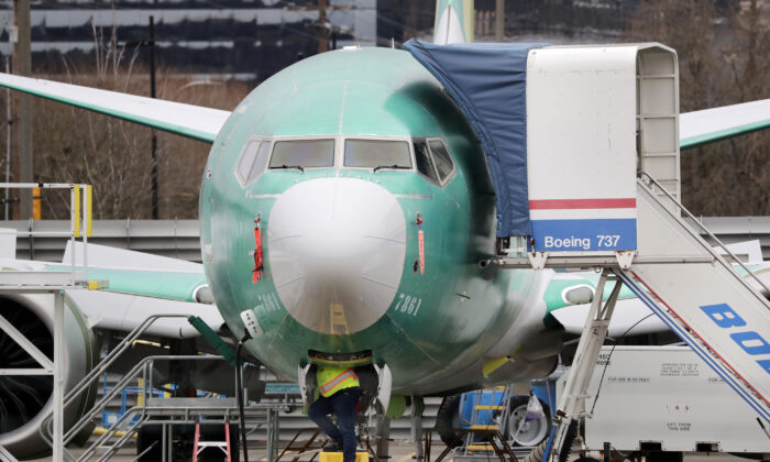 A worker looks up underneath a Boeing 737 MAX jet in Renton, Washington, on Dec. 16, 2019. (Elaine Thompson/AP)