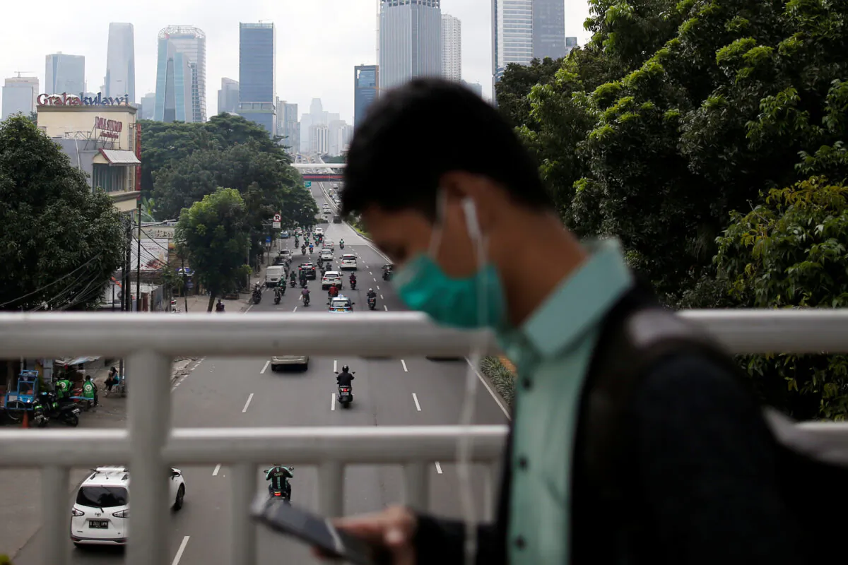 A man wearing protective mask uses his phone as he walks on a pedestrian bridge, following the outbreak of the new coronavirus in China, in Jakarta, Indonesia, on Feb. 13, 2020. (Willy Kurniawan/Reuters)