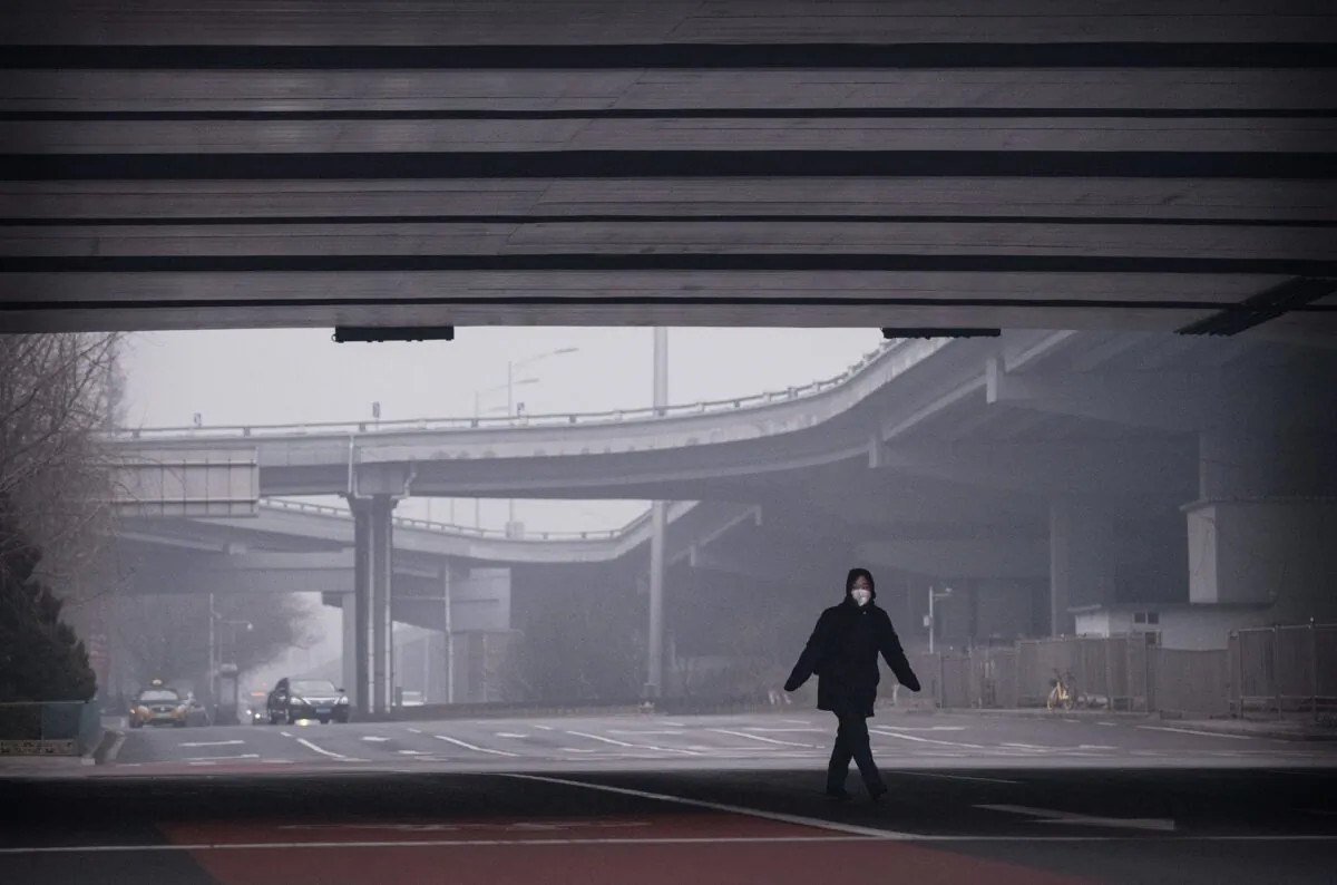 A Chinese woman wears a protective mask as she crosses a nearly empty intersection in Beijing, China, on Feb. 13, 2020. (Kevin Frayer/Getty Images)