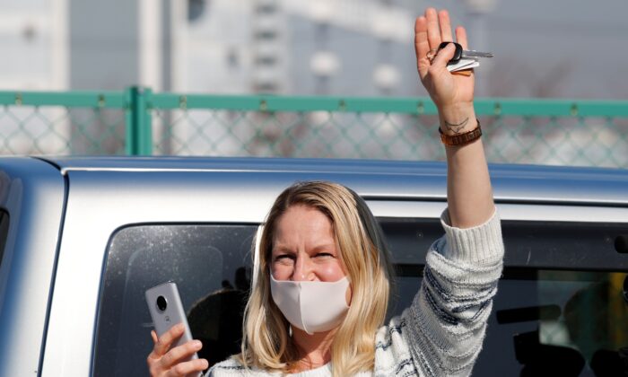 A woman waves from outside Daikoku Pier Cruise Terminal as she communicates via phone with a passenger (not pictured) standing o­n the balcony of a cabin o­n the cruise ship Diamond Princess, as the vessel's passengers continue to be tested for coronavirus, in Yokohama, south of Tokyo, Japan o­n Feb. 13, 2020. (Kim Kyung-Hoon/Reuters)