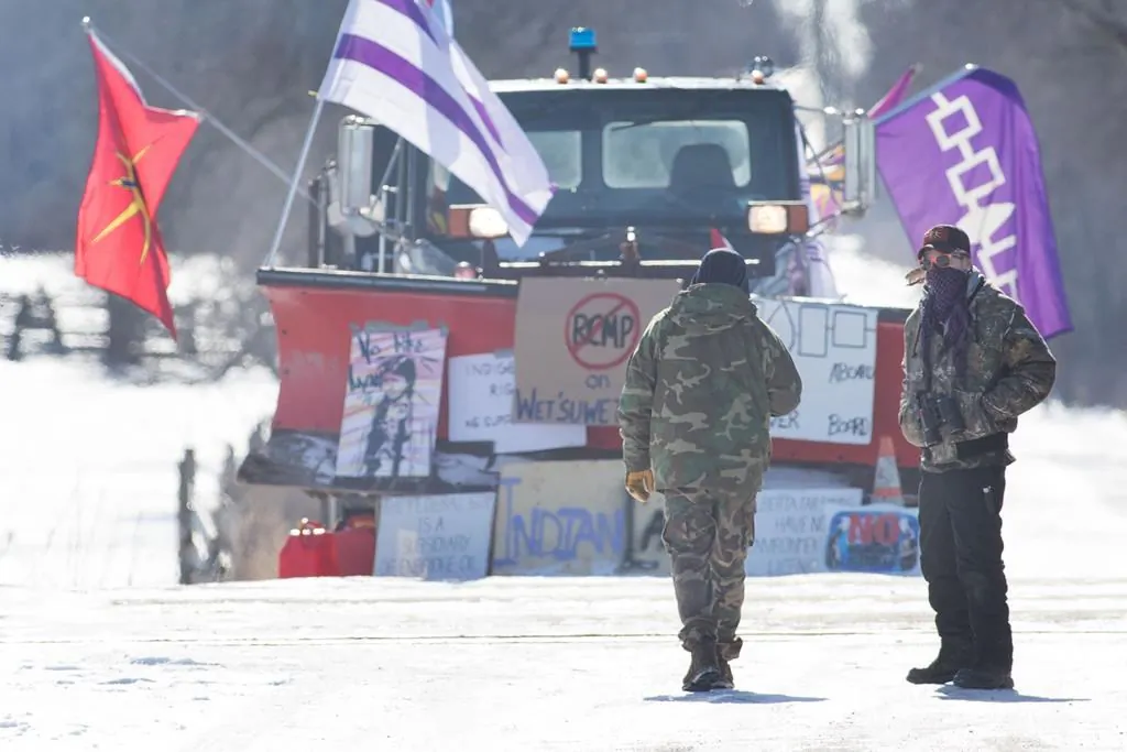 Land protectors stand on the closed train track on the ninth day of the blockade in Tyendinaga, near Belleville, Ont., on Feb. 14, 2020, as they protest in solidarity with the Wet'suwet'en hereditary chiefs opposed to the LNG pipeline in northern British Columbia. (Lars Hagberg/Canadian Press)