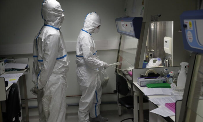 French lab scientists in hazmat gear inserting liquid in test tube manipulate potentially infected patient samples at Pasteur Institute in Paris on Feb. 6, 2020. (Francois Mori/AP Photo) 