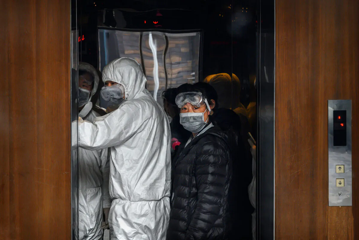 Chinese workers wearing protective suits stand in an elevator at a mall in Beijing, China, on Feb. 9, 2020. (Kevin Frayer/Getty Images)