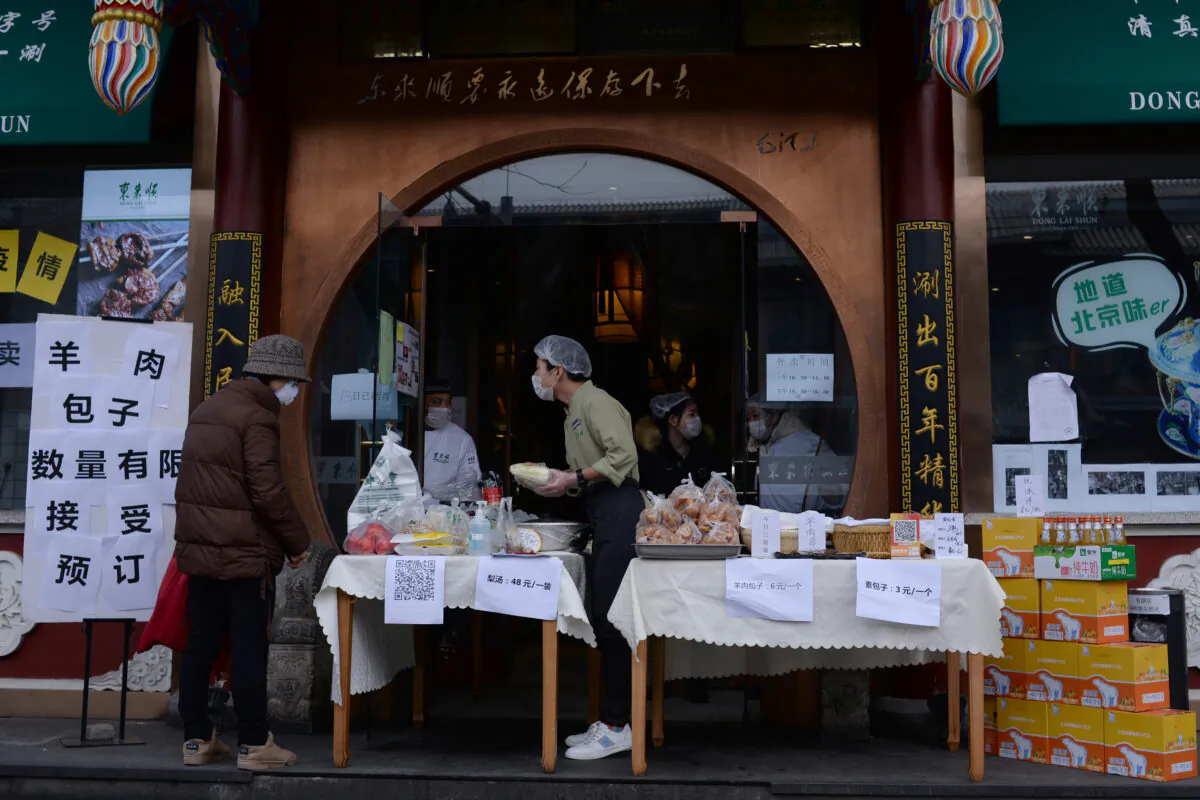A customer wearing a face mask buys vegetables from a stall set up by a hotpot restaurant outside its outlet in central Beijing, following an outbreak of the novel coronavirus in China, on Feb. 13, 2020. (Tingshu Wang/Reuters)