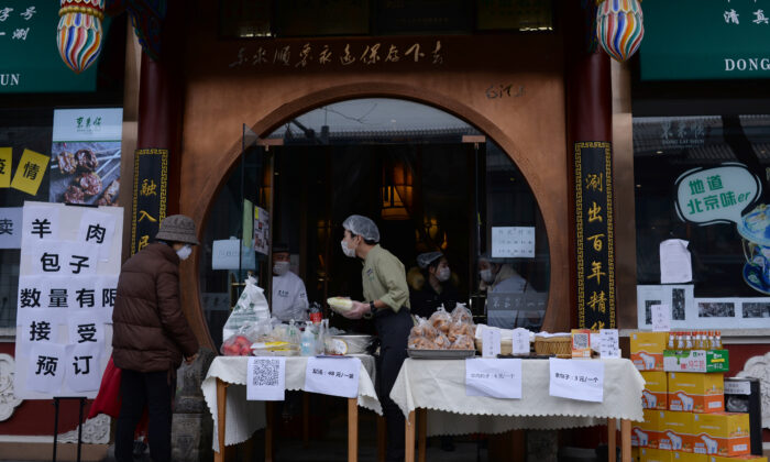 A customer wearing a face mask buys vegetables from a stall set up by a hotpot restaurant outside its outlet in central Beijing, following an outbreak of the novel coronavirus in China, on Feb. 13, 2020. (Tingshu Wang/Reuters)