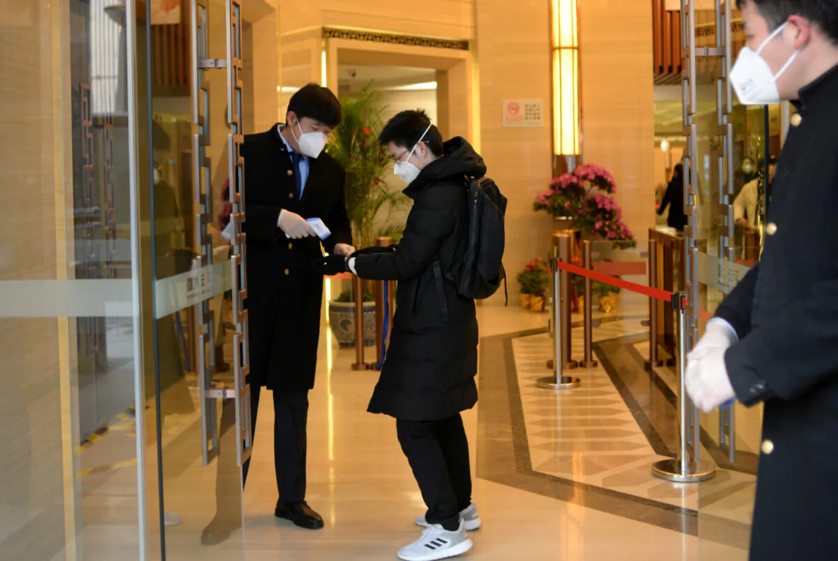 Jin Yang, 28, who works in a department of China's State Administration of Foreign Exchange, has his temperature checked at an entrance to his office, in the morning on his first day of returning to work after the extended Lunar New Year holiday caused by the novel coronavirus outbreak, in Beijing, China, on Feb. 10, 2020. (Tingshu Wang/Reuters)