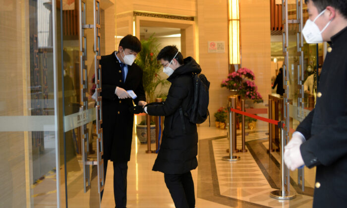 Jin Yang, 28, who works in a department of China's State Administration of Foreign Exchange, has his temperature checked at an entrance to his office, in the morning on his first day of returning to work after the extended Lunar New Year holiday caused by the novel coronavirus outbreak, in Beijing, China, on Feb. 10, 2020. (Tingshu Wang/Reuters)