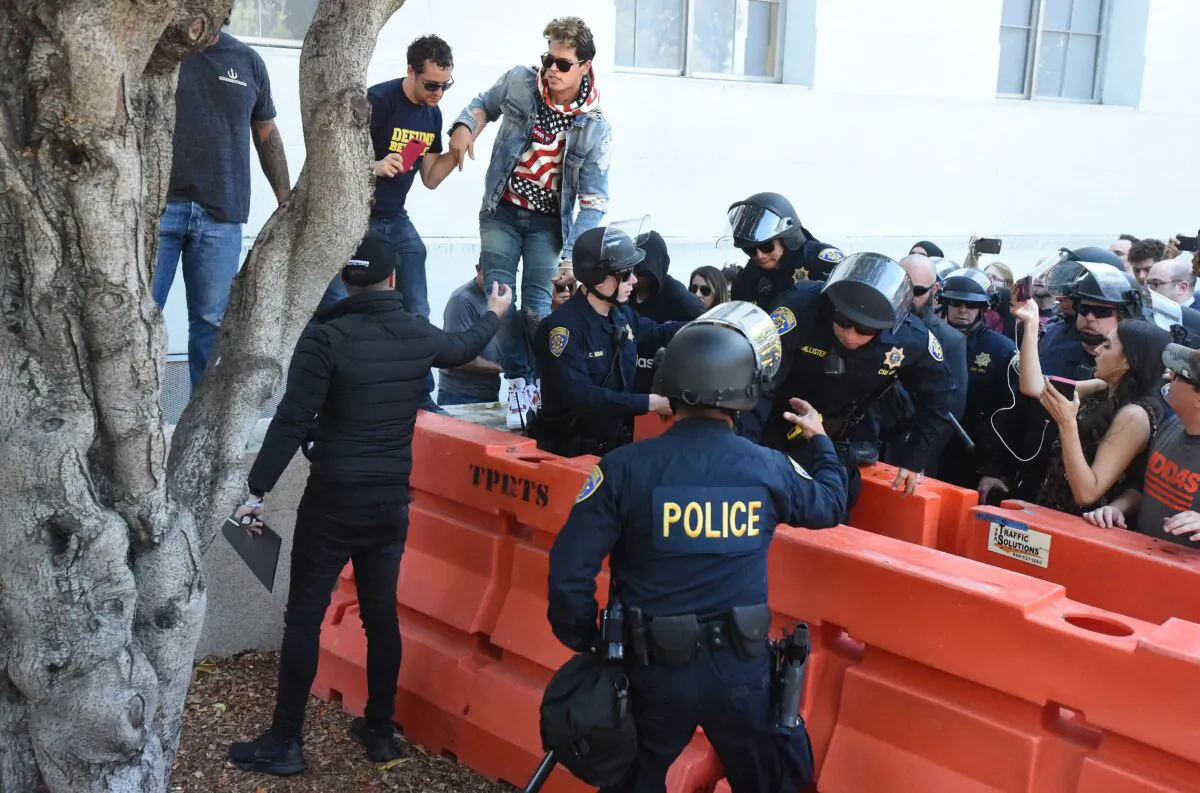 Conservative commentator Milo Yiannopoulos climbs over a barrier as he is escorted out of the University of California, Berkeley campus where he spoke to dozens of supporters on Sept. 24, 2017. 
(Josh Edelson/AFP via Getty Images)